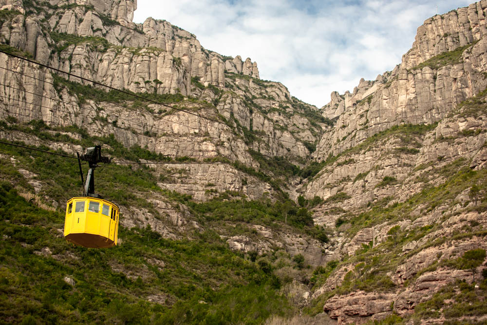 Yellow cable car going up into Montserrat mountains